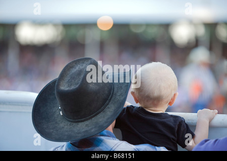 Vue arrière de l'Homme tenant un enfant sur Rodeo, Belle Fourche, South Dakota, USA Banque D'Images