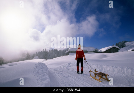 Jeune femme tirant un traîneau sur tobbogan exécuter près de hut Lustenauer Huette, Schwarzenberg, Forêt Noire, Vorarlberg, Autriche Banque D'Images