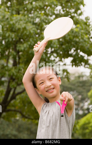 Girl holding une raquette et un volant dans un jardin Banque D'Images