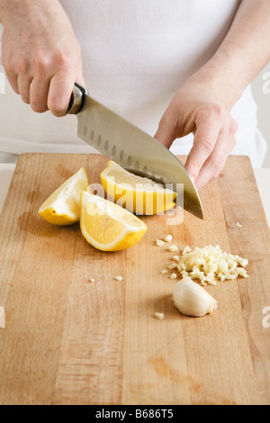 Woman Slicing Citrons et l'Ail Banque D'Images