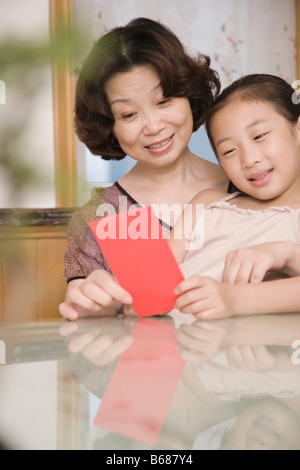 Femme mature avec une fille à la recherche à une carte de vœux et souriant Banque D'Images