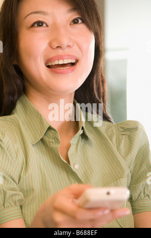 Close-up of a young woman holding a télécommande et rire Banque D'Images