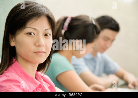 Portrait d'une femme employée de bureau avec deux autres employés de bureau, assis près d'elle Banque D'Images