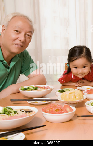 Portrait d'un homme mûr assis avec sa petite-fille à une table à manger Banque D'Images