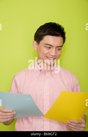 Male office worker holding documents dans ses mains et souriant Banque D'Images