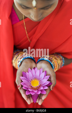 Femme indienne offrant un Nymphaea nénuphar Tropical flower in her creux des mains. L'Andhra Pradesh, Inde Banque D'Images