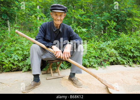 Portrait d'un agriculteur assis sur un tabouret dans un champ, Zhigou, Shandong Province, China Banque D'Images