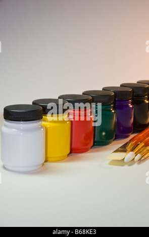 Les peintures et les pinceaux de l'artiste assise sur une table avec un fond blanc. Banque D'Images