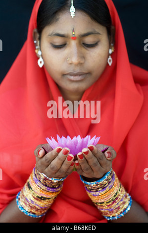 Femme indienne offrant un Nymphaea nénuphar Tropical flower dans un sari rouge Banque D'Images