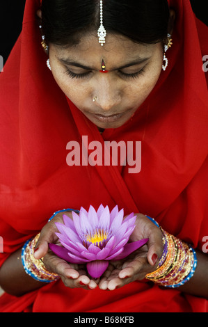 Femme indienne offrant un Nymphaea nénuphar Tropical flower dans un sari rouge. L'Andhra Pradesh, Inde Banque D'Images