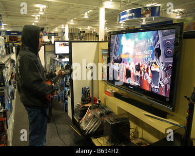Un jeune homme essayer les derniers Guitar Hero dans un magasin d'électronique. Banque D'Images