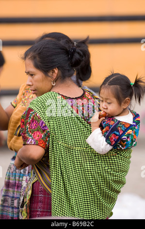 Les femme portant enfant en écharpe colorée en costume traditionnel. Santa Maria de Jesus, au Guatemala Banque D'Images