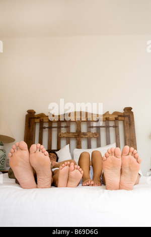 Plante de couple et leurs enfants et les pieds sur le lit Banque D'Images