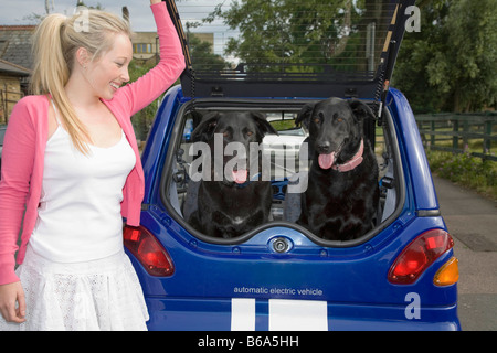 Jeune femme de mettre les chiens dans la voiture électrique Banque D'Images