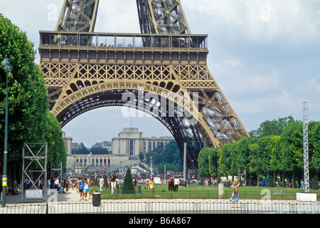 La Tour Eiffel, Paris, contre ciel nuageux Ciel bleu avec de l'herbe et les arbres le parc du Champ-de-Mars. Banque D'Images