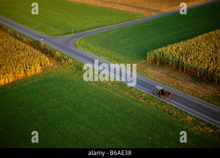 Vue aérienne de Amish buggy tiré par des chevaux sur une route rurale au coucher du soleil, le comté de Lancaster, Pennsylvanie, USA Banque D'Images