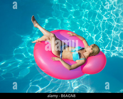 Femme en fauteuil gonflable dans la piscine Banque D'Images