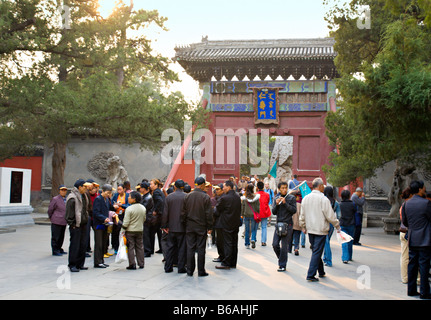 BEIJING CHINE groupe de voyageurs chinois portant des casquettes de baseball et guide suivant avec un drapeau dans le Palais d'été. Banque D'Images