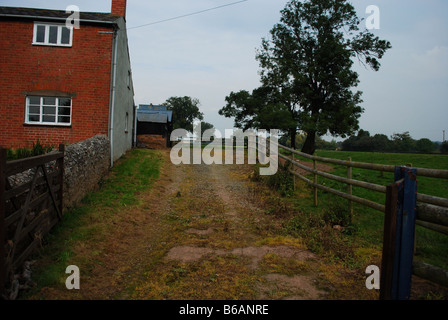 Allée le long du côté d'une vieille maison de ferme en brique rouge, Hereford, Angleterre, RU Banque D'Images