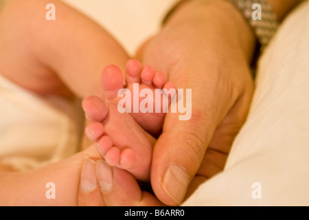 Les pieds du nouveau-né sont maintenus par le père Banque D'Images