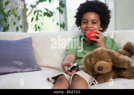 African boy eating apple et regarder la télévision Banque D'Images