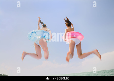 Deux jeunes femmes en bikini jumping Banque D'Images