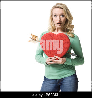 Femme tenant un cœur avec une flèche à travers elle Banque D'Images