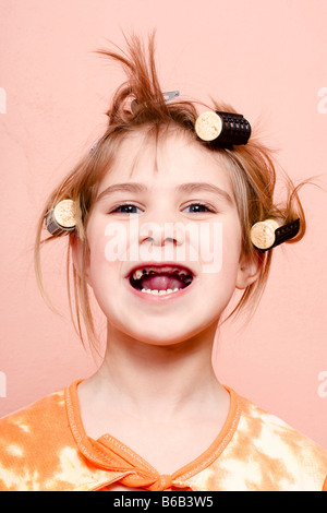 Sans dents petite fille de 6 ans avec un sourire parfait et les bigoudis en intérieur Banque D'Images