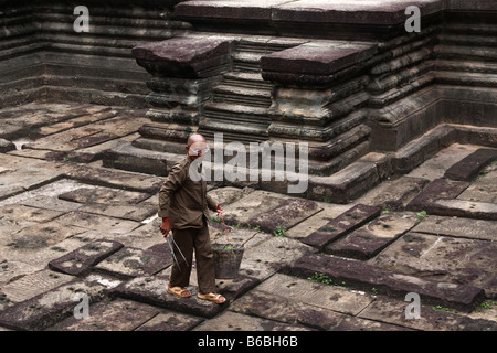 Vieux moine en robes de travail nettoyage de l'intérieur du temple d'Angkor Wat Banque D'Images