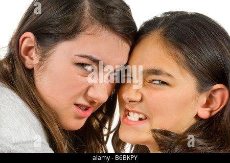 Close up portrait of horizontal de deux sœurs adolescentes grondant menaçant lors d'un combat contre un fond blanc Banque D'Images