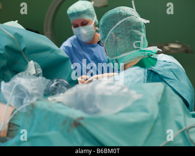 Chirurgiens performing operation in operating room Banque D'Images