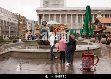 Une fille à l'aide d'un téléphone mobile, en face de la rivière statue au Marché de Noël de Birmingham une tasse géante est titulaire d'un parapluie Banque D'Images