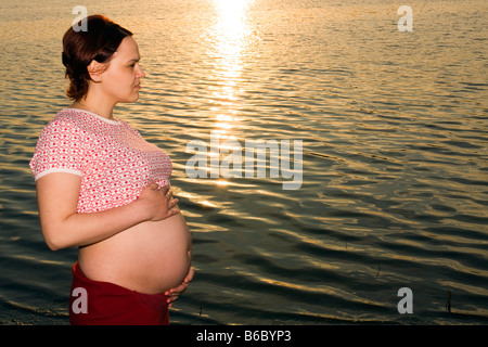 Femme enceinte 28 ans et coucher du soleil à l'extérieur Banque D'Images