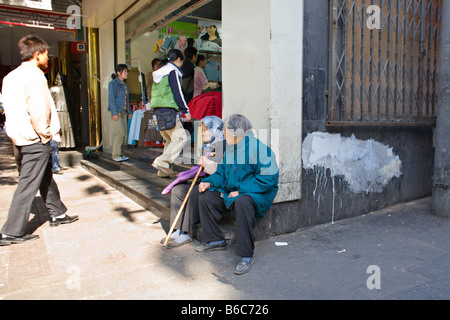 Chine Pékin deux vieilles femmes chinoises s'asseoir ensemble à l'entrée d'un grand magasin comme les jeunes qui se lancent dans l'embrasure Banque D'Images