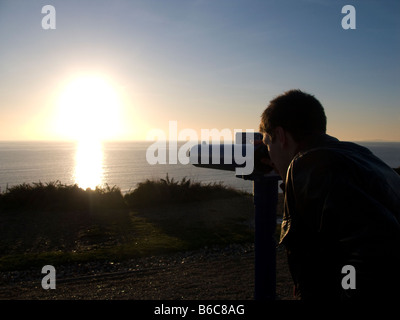 L'homme face à la mer à travers un télescope touristique à monnayeur, Lymington, Hampshire Banque D'Images