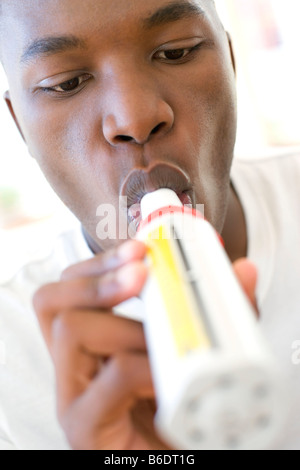 L'homme souffle dans un débitmètre de pointe pour surveiller son asthme Banque D'Images
