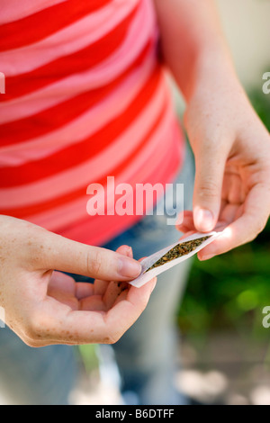 L'usage du cannabis. Teenage girl préparer une cigarette à base de tabac et de cannabis. Banque D'Images