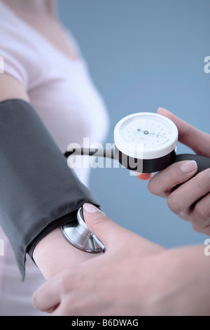 La mesure de la pression artérielle. Vingt-cinq ans, femme qui a son pressurechecked du sang à l'aide d'un sphygmomanomètre. Banque D'Images