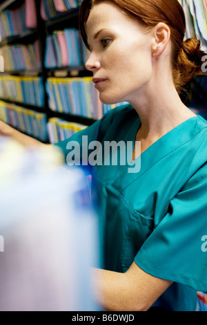 Les dossiers médicaux. Infirmière recherche à travers des dossiers médicaux dans un débarras. Banque D'Images