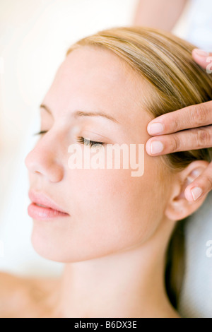 Woman receiving massage du temple qui peut soulager la douleur ou raideur musculaire en stimulant le flux sanguin à la zone affectée Banque D'Images