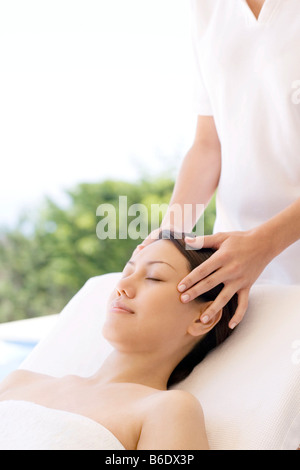 Woman receiving massage du temple qui peut soulager la douleur ou raideur musculaire en stimulant le flux sanguin à la zone affectée Banque D'Images