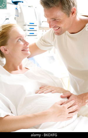 Pregant woman dans un lit d'hôpital à la recherche de son partenaire. Banque D'Images