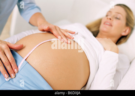 Examen obstétrique. Sage-femme, mesurer la taille de l'abdomen de la femme enceinte. Banque D'Images