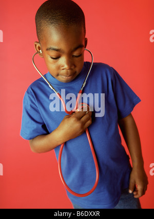 L'examen de conscience. Garçon de 6 ans à l'écoute de son rythme cardiaque à l'aide d'un stéthoscope. Banque D'Images