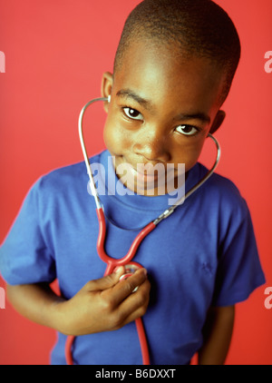 L'examen de conscience. Garçon de 6 ans à l'écoute de son rythme cardiaque à l'aide d'un stéthoscope. Banque D'Images