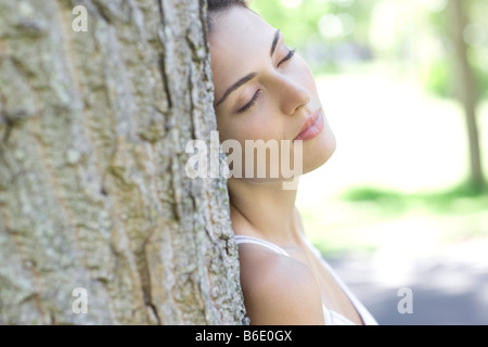 Happy woman leaning against tree Banque D'Images