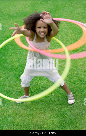 Jeune fille jouant avec un cerceau dans un jardin. Banque D'Images