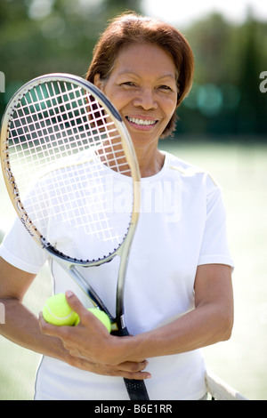 Joueur de tennis. Femme tenant une raquette de tennis et de boules, debout près d'un filet de tennis. Banque D'Images