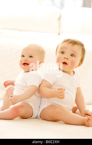 Les bébés. Baby Girl (à gauche) et garçon (à droite) assis à côté de l'autre Banque D'Images