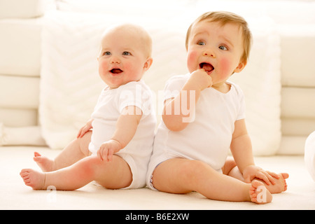 Les bébés. Baby Girl (à gauche) et garçon (à droite) assis à côté de l'autre Banque D'Images